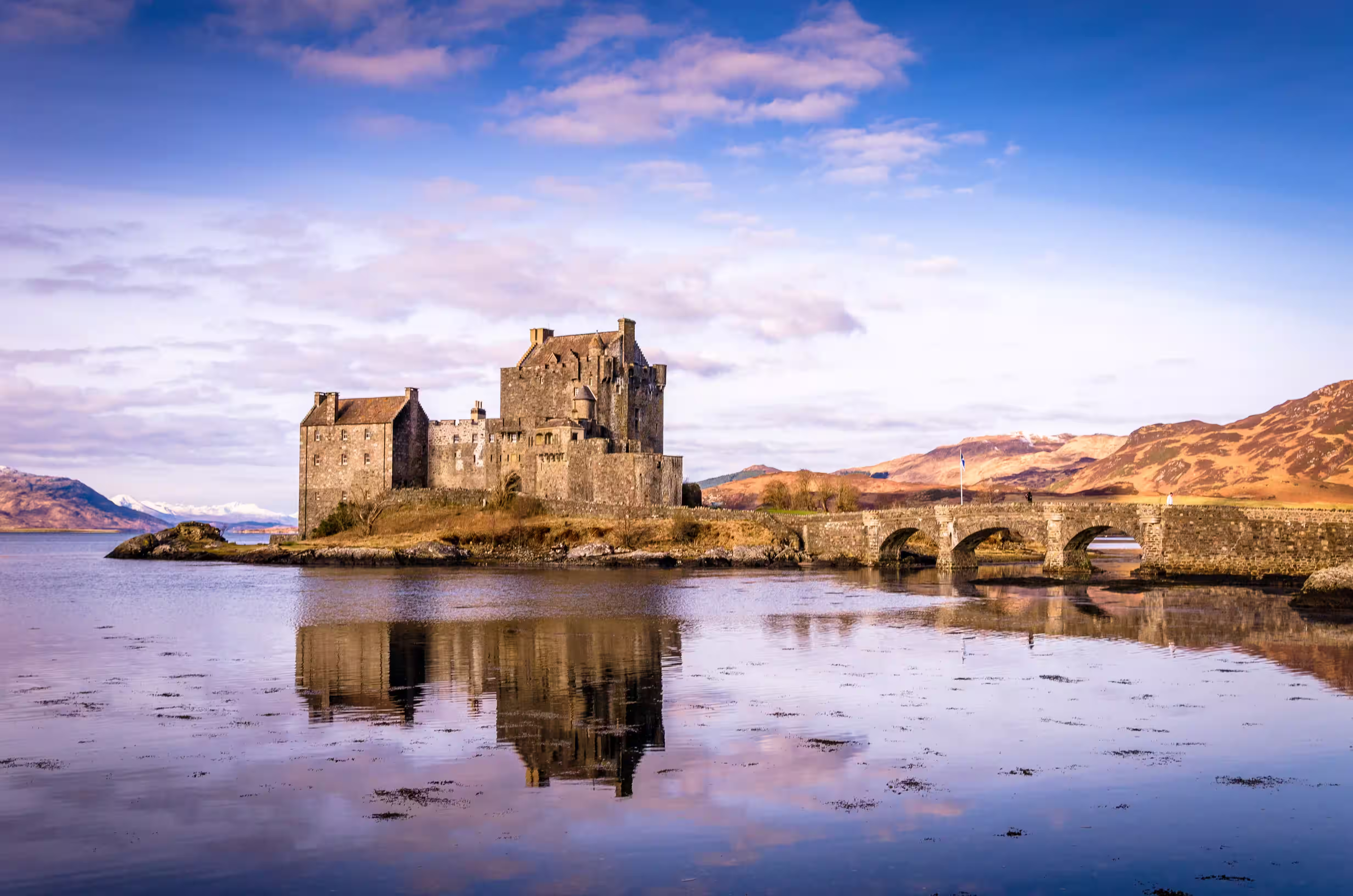 Castillo de Eilean Donan rodeado de agua y montañas en las Highlands.